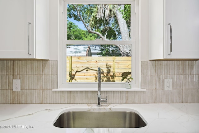 771 W 4th St, Saint Augustine, FL 32084 - kitchen view of a sink, white cabinetry, and backsplash