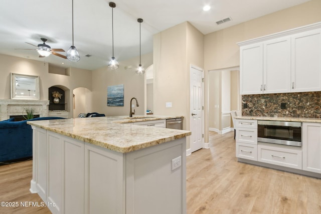 86569 N Hampton Club Way, Fernandina Beach, FL 32034 - kitchen with appliances with stainless steel finishes, a sink, a fireplace, a ceiling fan, and arched walkways