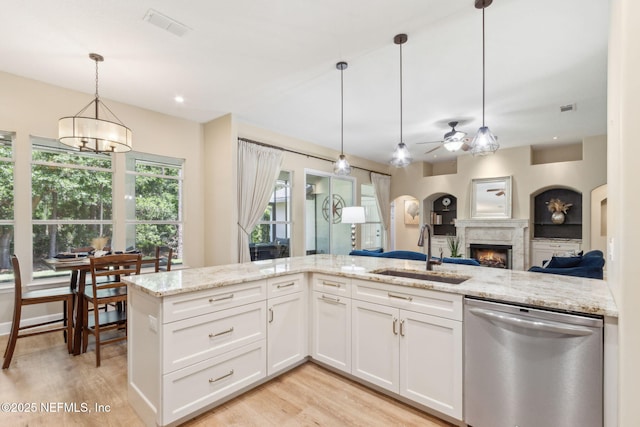 86569 N Hampton Club Way, Fernandina Beach, FL 32034 - kitchen with stainless steel dishwasher, a sink, ceiling fan, light wood-style flooring, and a warm lit fireplace