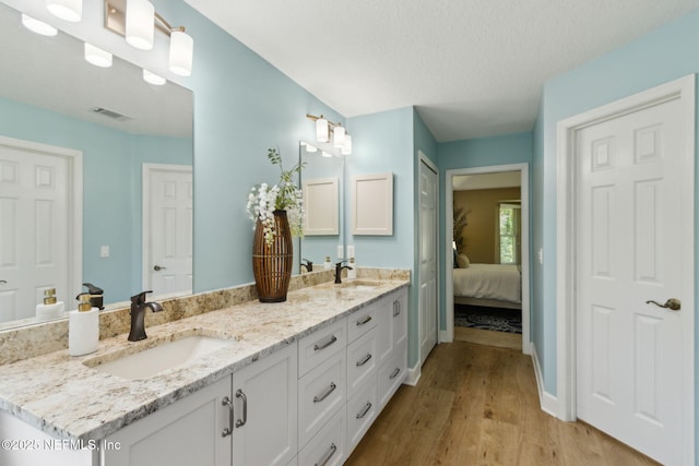 86569 N Hampton Club Way, Fernandina Beach, FL 32034 - ensuite bathroom featuring double vanity, wood finished floors, baseboards, and a textured ceiling