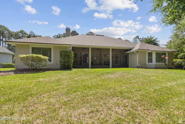 86569 N Hampton Club Way, Fernandina Beach, FL 32034 - back of property with a sunroom, a lawn, a chimney, roof with shingles, and stucco siding