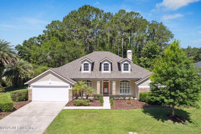 86569 N Hampton Club Way, Fernandina Beach, FL 32034 - cape cod house featuring stone siding, an attached garage, stucco siding, and a front lawn