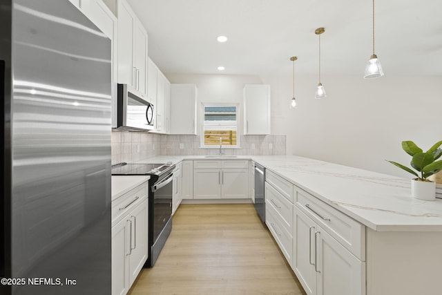 763 W 4th St, Saint Augustine, FL 32084 - kitchen featuring appliances with stainless steel finishes, a peninsula, tasteful backsplash, light wood-style flooring, and light stone counters