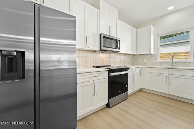 763 W 4th St, Saint Augustine, FL 32084 - kitchen with appliances with stainless steel finishes, light wood-style flooring, white cabinets, light countertops, and recessed lighting