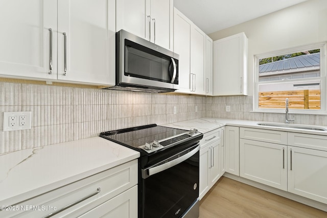 763 W 4th St, Saint Augustine, FL 32084 - kitchen featuring stainless steel microwave, range with electric cooktop, a sink, white cabinets, and decorative backsplash