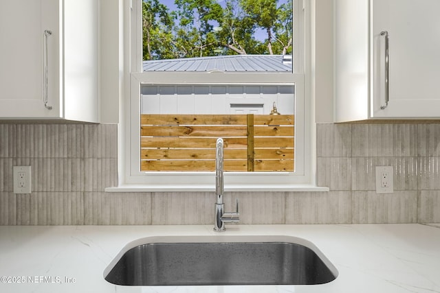 763 W 4th St, Saint Augustine, FL 32084 - kitchen view of a sink, tasteful backsplash, white cabinets, and light stone countertops