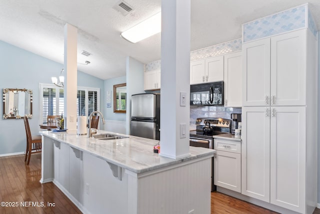 118 Governor St Unit 208, Green Cove Springs, FL 32043 - kitchen with stainless steel appliances, a sink, wood finished floors, white cabinetry, and lofted ceiling