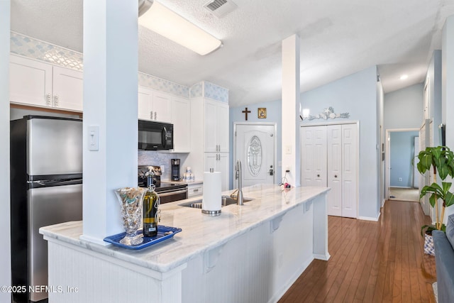 118 Governor St Unit 208, Green Cove Springs, FL 32043 - kitchen with appliances with stainless steel finishes, a sink, white cabinets, dark wood-style floors, and light stone countertops