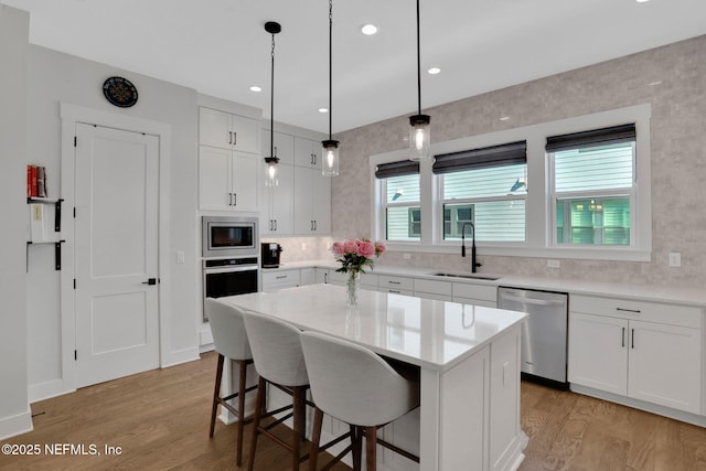 1622 Bridgeton Dr, Jacksonville, FL 32207 - kitchen featuring stainless steel appliances, a sink, light wood-style flooring, a kitchen breakfast bar, and white cabinets