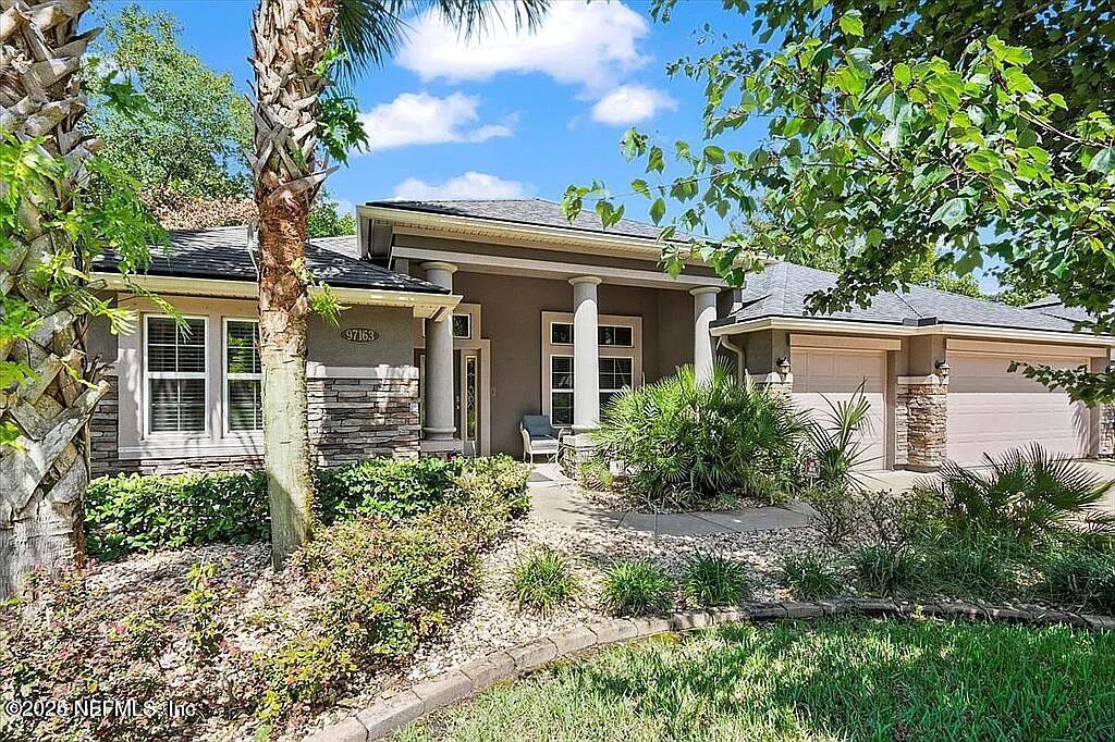 97163 Bluff View Cir, Yulee, FL 32097 - view of front of home with stone siding, stucco siding, an attached garage, and a shingled roof