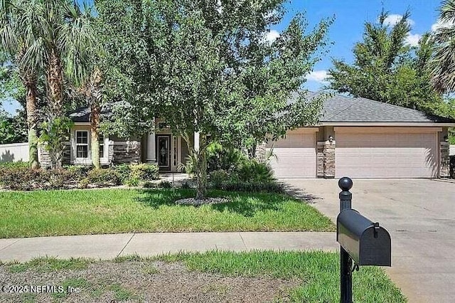 97163 Bluff View Cir, Yulee, FL 32097 - view of property hidden behind natural elements with driveway, a garage, a front yard, and stone siding