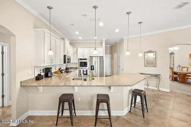 97163 Bluff View Cir, Yulee, FL 32097 - kitchen with stainless steel appliances, arched walkways, a peninsula, white cabinetry, and ornamental molding