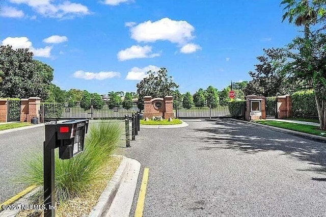 97163 Bluff View Cir, Yulee, FL 32097 - view of asphalt road featuring curbs, a gate, traffic signs, a gated entry, and sidewalks