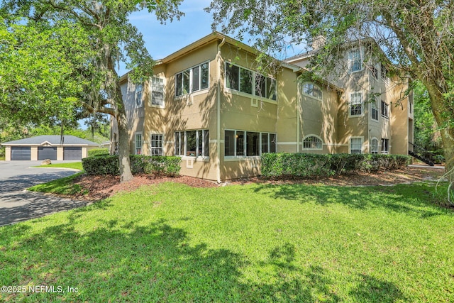 1655 The Greens Way Unit 3416, Jacksonville Beach, FL 32250 - back of property with stucco siding, a detached garage, a yard, and a chimney