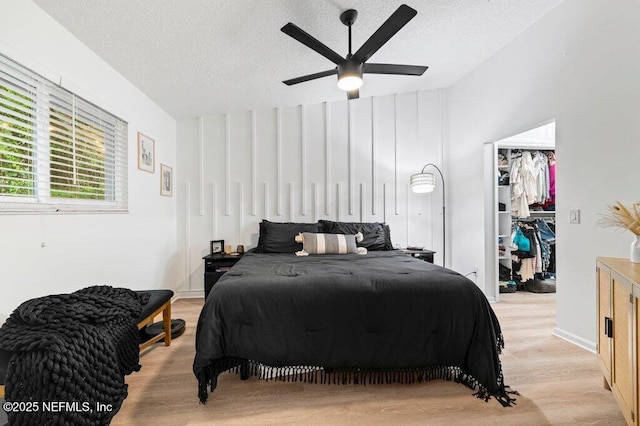 2275 Fairway Villas Ln N, Atlantic Beach, FL 32233 - bedroom with light wood-type flooring, a textured ceiling, a walk in closet, a closet, and ceiling fan
