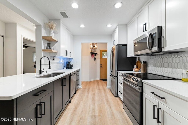 2275 Fairway Villas Ln N, Atlantic Beach, FL 32233 - kitchen featuring stainless steel appliances, open shelves, a sink, white cabinetry, and light wood-type flooring