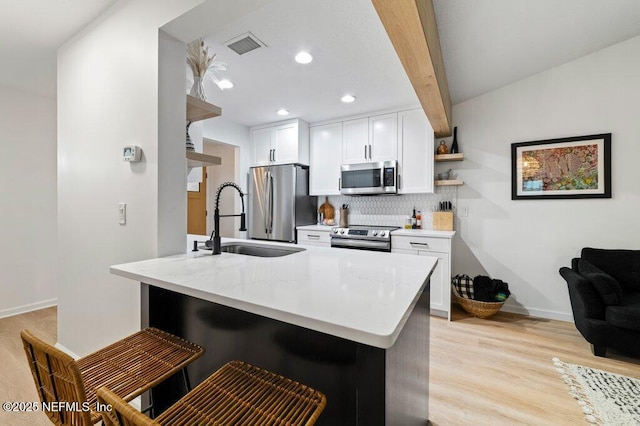 2275 Fairway Villas Ln N, Atlantic Beach, FL 32233 - kitchen featuring appliances with stainless steel finishes, a sink, decorative backsplash, light wood-style floors, and a breakfast bar