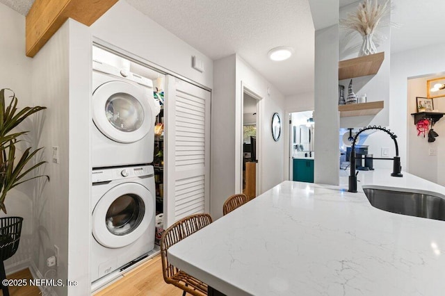 2275 Fairway Villas Ln N, Atlantic Beach, FL 32233 - washroom with stacked washer / dryer, a textured ceiling, and light wood-type flooring