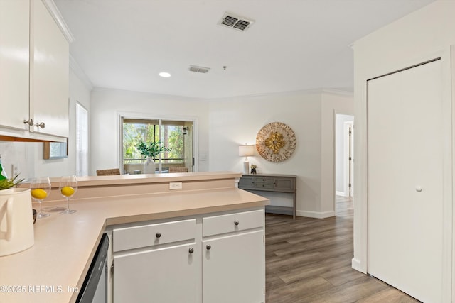 1655 The Greens Way Unit 3021, Jacksonville Beach, FL 32250 - kitchen featuring crown molding, a peninsula, light countertops, light wood-style floors, and white cabinets