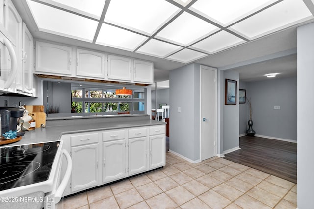 2279 Seminole Rd Unit 11, Atlantic Beach, FL 32233 - kitchen featuring white cabinetry, light tile patterned flooring, range with electric cooktop, baseboards, and light countertops