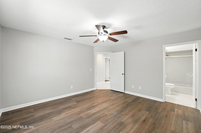 257 Jasmine St, Atlantic Beach, FL 32233 - unfurnished bedroom featuring wood finished floors, baseboards, ceiling fan, ensuite bathroom, and a textured ceiling