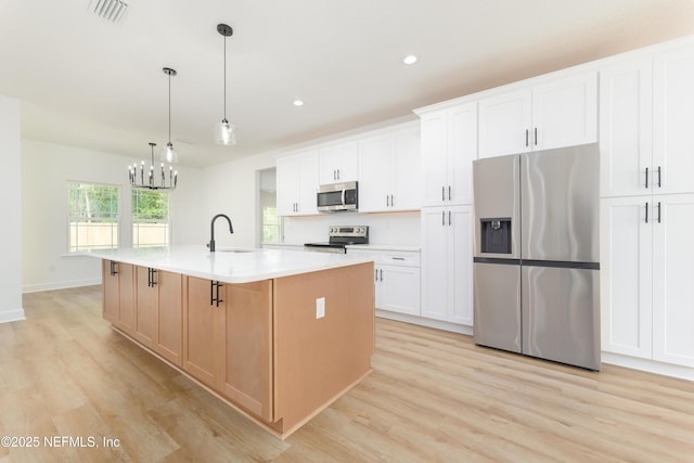 1873 Openwoods Rd, Middleburg, FL 32068 - kitchen with stainless steel appliances, a sink, light wood-style floors, a center island with sink, and recessed lighting