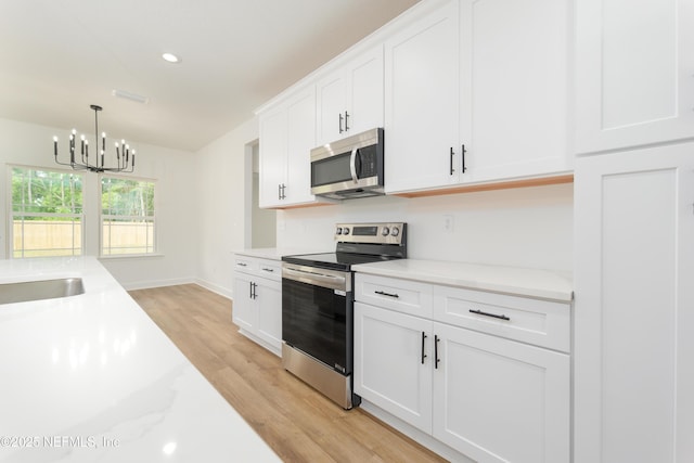 1873 Openwoods Rd, Middleburg, FL 32068 - kitchen with stainless steel appliances, light wood-style flooring, a chandelier, light countertops, and recessed lighting