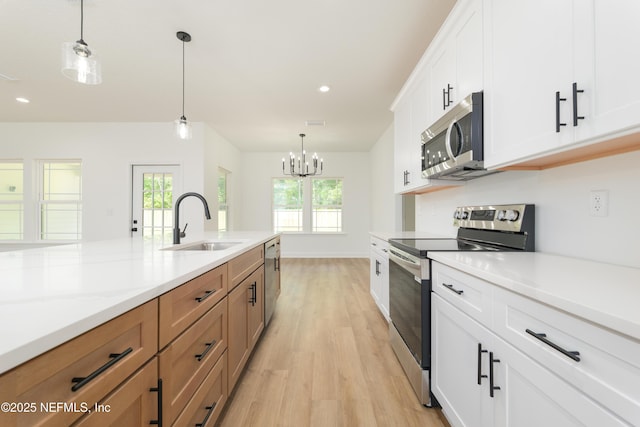 1873 Openwoods Rd, Middleburg, FL 32068 - kitchen featuring stainless steel appliances, light wood-style flooring, a sink, brown cabinetry, and pendant lighting