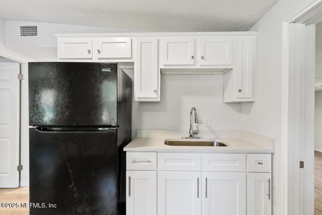 4249 Lockhart Dr, Jacksonville, FL 32209 - kitchen with freestanding refrigerator, a sink, light countertops, and white cabinetry