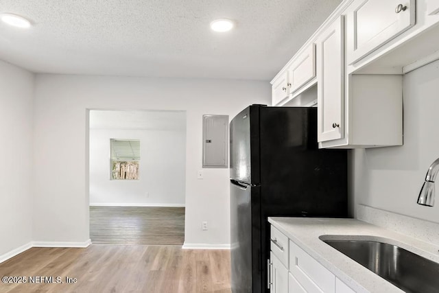 4249 Lockhart Dr, Jacksonville, FL 32209 - kitchen with a sink, electric panel, a textured ceiling, freestanding refrigerator, and light wood finished floors