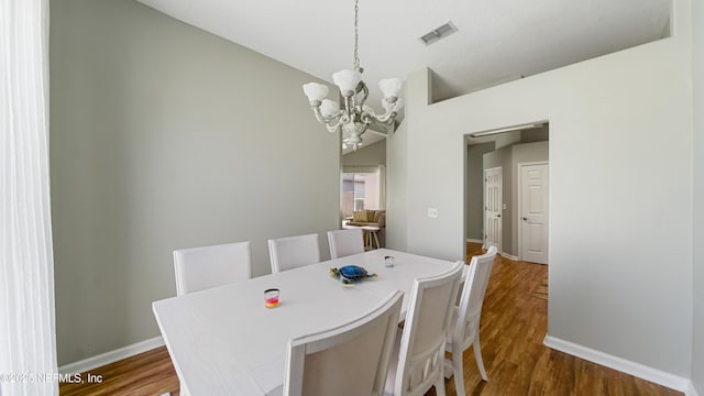 165 Cedar Ridge Cir, Saint Augustine, FL 32080 - dining space with a chandelier, vaulted ceiling, dark wood-style floors, and baseboards