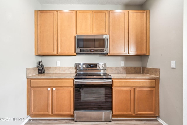 6033 Bartram Village Dr, Jacksonville, FL 32258 - kitchen featuring appliances with stainless steel finishes, light wood finished floors, light countertops, and baseboards