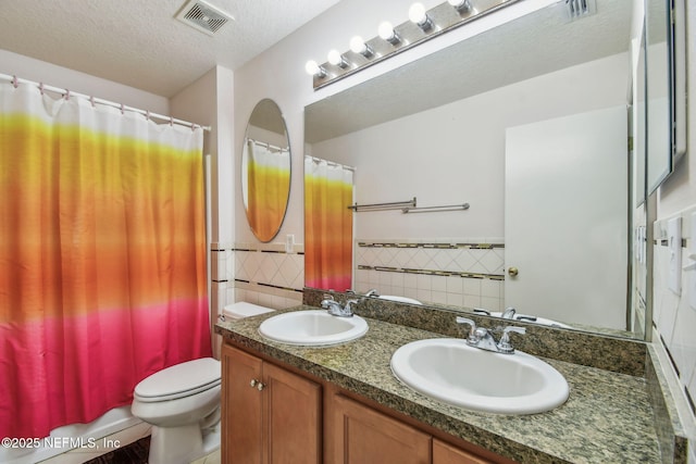 116 Nunna Rock Trl, Saint Augustine, FL 32092 - bathroom with tile walls, double vanity, toilet, a wainscoted wall, and a textured ceiling