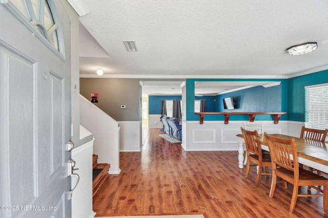 116 Nunna Rock Trl, Saint Augustine, FL 32092 - dining space with ornamental molding, wood finished floors, wainscoting, a textured ceiling, and stairs