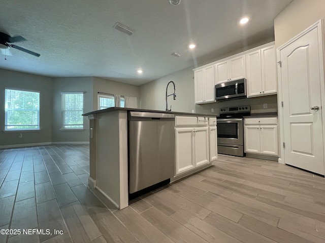 10312 Benson Lake Dr, Jacksonville, FL 32222 - kitchen featuring appliances with stainless steel finishes, light wood-style floors, dark countertops, a ceiling fan, and open floor plan