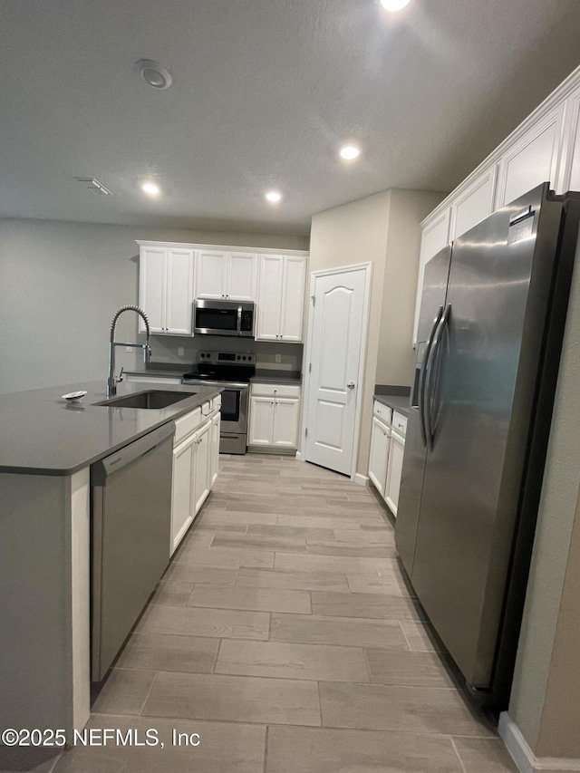 10312 Benson Lake Dr, Jacksonville, FL 32222 - kitchen with stainless steel appliances, a sink, light wood-style floors, white cabinetry, and recessed lighting