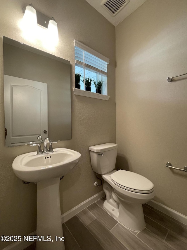 10312 Benson Lake Dr, Jacksonville, FL 32222 - half bathroom with toilet, wood tiled floors, baseboards, and a sink