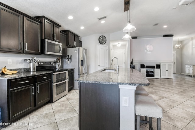 75 Codman Dr, Saint Augustine, FL 32084 - kitchen with appliances with stainless steel finishes, a sink, light tile patterned flooring, dark stone counters, and a breakfast bar area