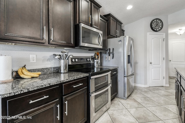 75 Codman Dr, Saint Augustine, FL 32084 - kitchen featuring appliances with stainless steel finishes, dark stone countertops, dark brown cabinetry, light tile patterned flooring, and a textured ceiling