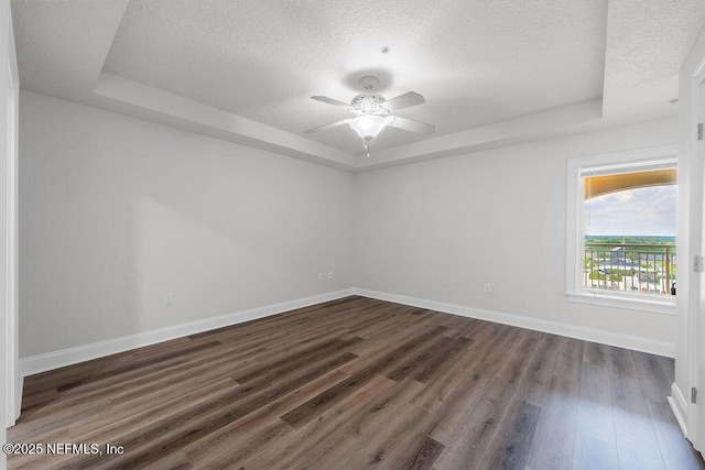 1201 1st St N Unit 1002, Jacksonville Beach, FL 32250 - spare room featuring a tray ceiling, dark wood-type flooring, a textured ceiling, baseboards, and a ceiling fan