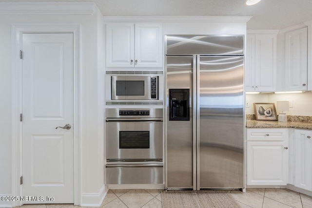 1201 1st St N Unit 1002, Jacksonville Beach, FL 32250 - kitchen featuring built in appliances, a warming drawer, light tile patterned floors, and white cabinets