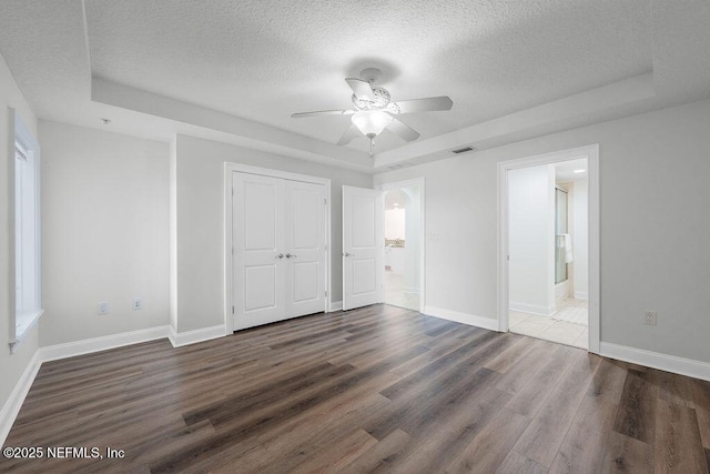1201 1st St N Unit 1002, Jacksonville Beach, FL 32250 - unfurnished bedroom featuring a raised ceiling, a textured ceiling, wood finished floors, baseboards, and ensuite bathroom