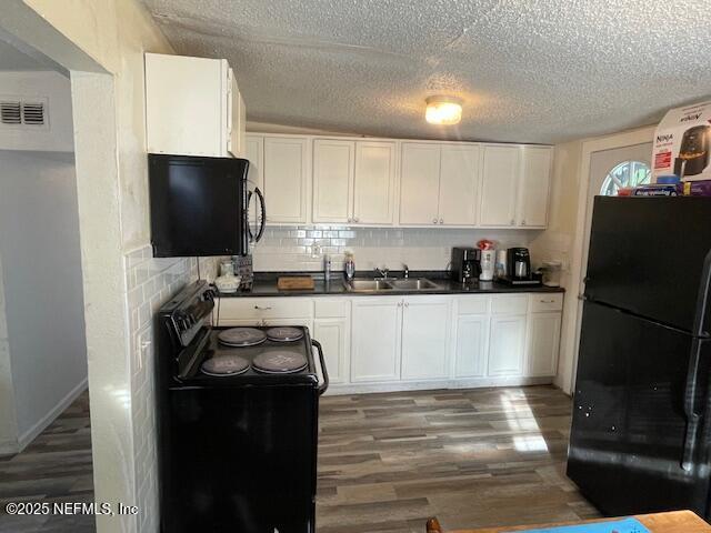 843 Line St, Jacksonville, FL 32209 - kitchen with black appliances, a sink, wood finished floors, dark countertops, and white cabinetry