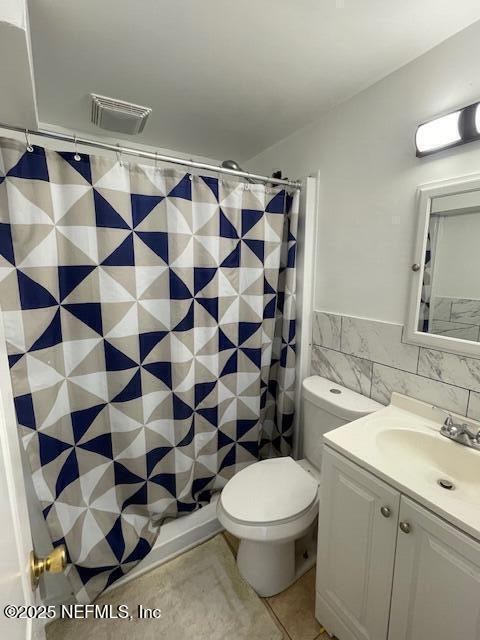 843 Line St, Jacksonville, FL 32209 - full bath featuring tile walls, vanity, tile patterned floors, toilet, and curtained shower