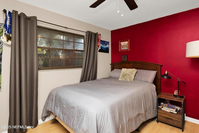3111 Old Port Cir E, Jacksonville, FL 32216 - bedroom with wood finished floors, baseboards, an accent wall, ceiling fan, and a textured ceiling