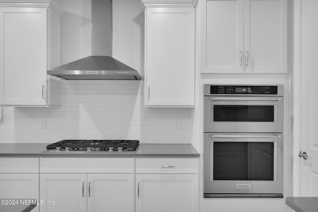45 Lantern Post Way, Ponte Vedra, FL 32081 - kitchen with wall chimney range hood, stainless steel appliances, white cabinets, tasteful backsplash, and dark countertops