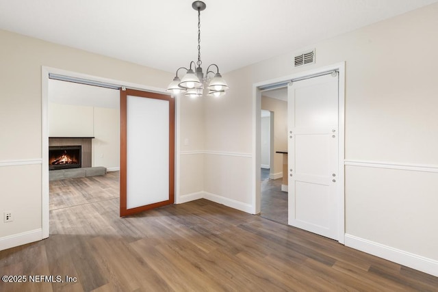 2605 Spreading Oaks Ln, Jacksonville, FL 32223 - unfurnished dining area featuring wood finished floors, a chandelier, baseboards, and a lit fireplace
