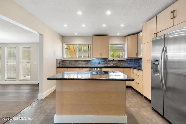 2605 Spreading Oaks Ln, Jacksonville, FL 32223 - kitchen featuring stainless steel refrigerator with ice dispenser, a center island, a textured ceiling, tasteful backsplash, and dark stone countertops