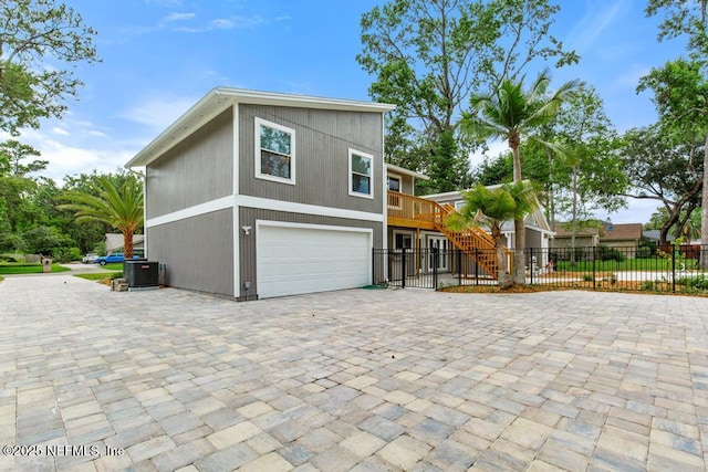 2605 Spreading Oaks Ln, Jacksonville, FL 32223 - view of side of home featuring an attached garage, decorative driveway, stairway, and central AC