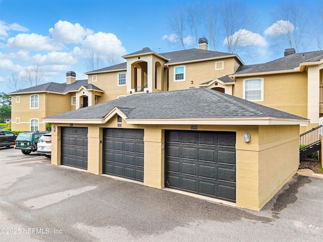 1655 The Greens Way Unit 2612, Jacksonville Beach, FL 32250 - view of front facade featuring community garages, stucco siding, and roof with shingles